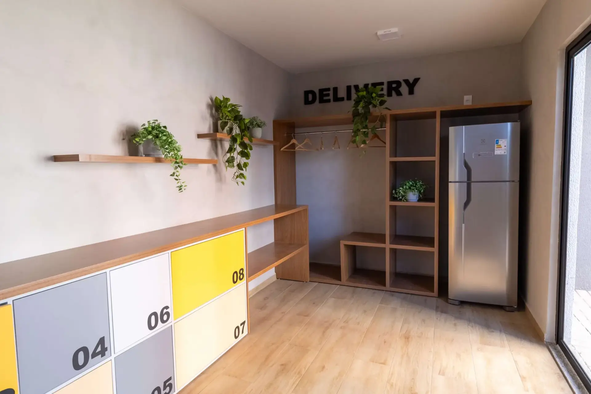 Sala de delivery do MEO Neoville entregue, com armários numerados, cabideiro e geladeira